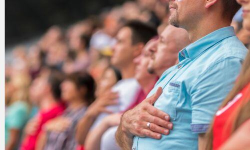 Crowd standing for the National Anthem with their hands over their hearts. Crowd standing for the National Anthem with their hands over their hearts.